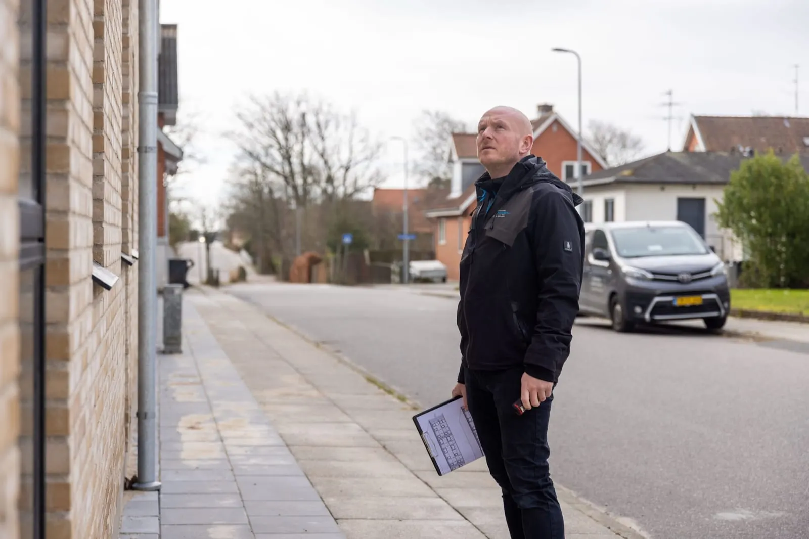 Byggesagkyndig efterser et murstenshus på en villavej