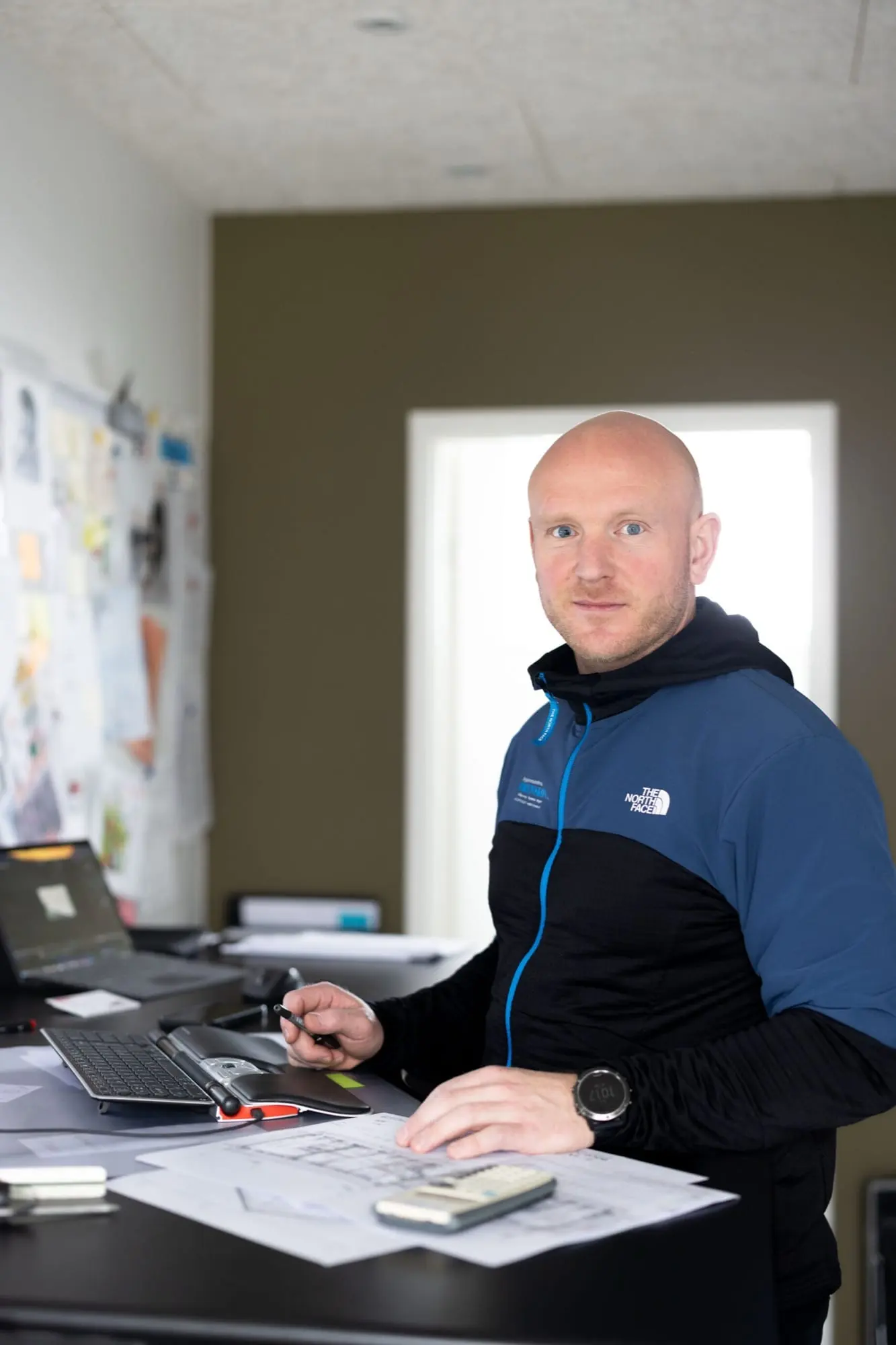 Byggesagkyndig ved skrivebordet med laptop og tegneplade