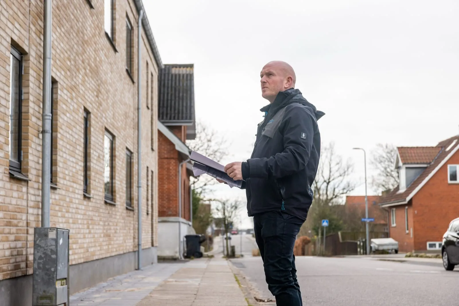 Byggesagkyndig inspicerer murstenshus med dokumenter i hånden